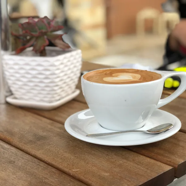 Sample photo: a cappuccino with latte art on a wooden table