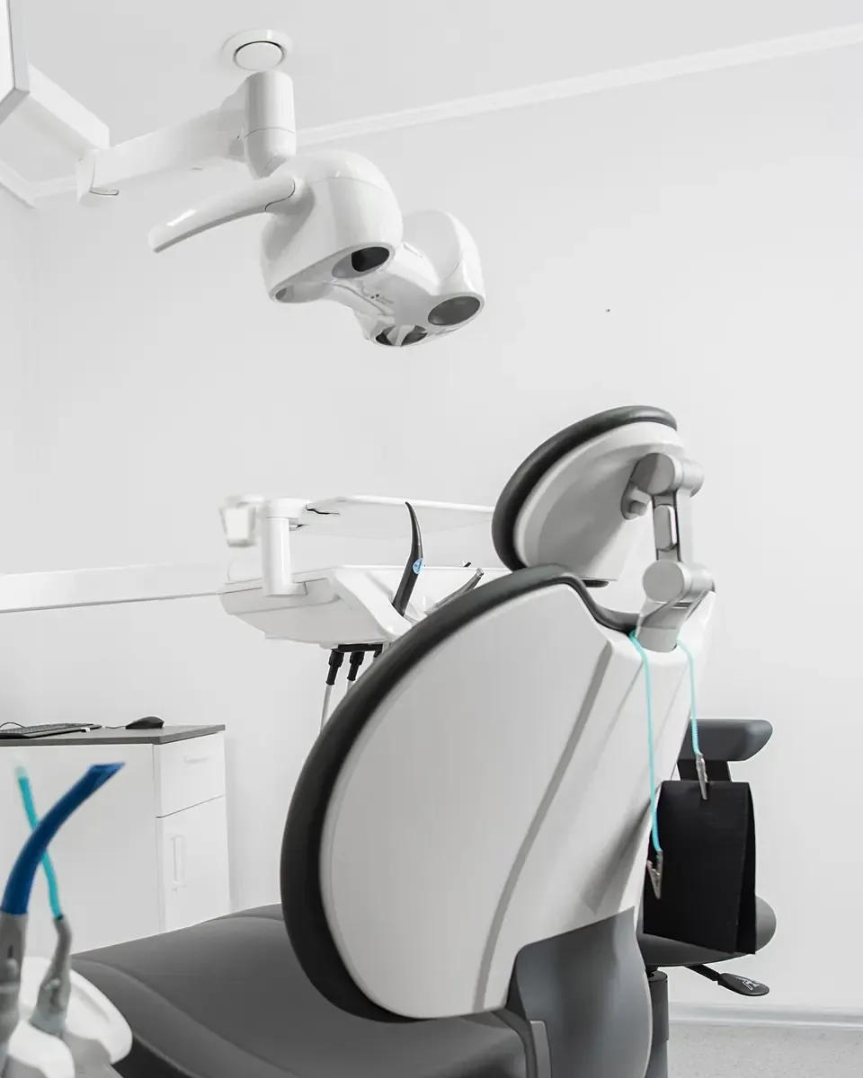 A bright, empty treatment room with a large window and a white chair.